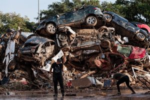 Varias personas limpian entre coches amontonados en Alfafar.