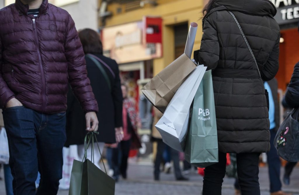 Archivo - Varias personas con bolsas de la compra en una calle céntrica. 